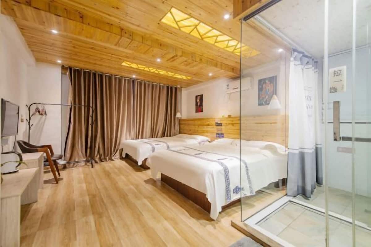 Hotellihuone, jossa on puulattia, sänky, työpöytä ja lasiseinä.