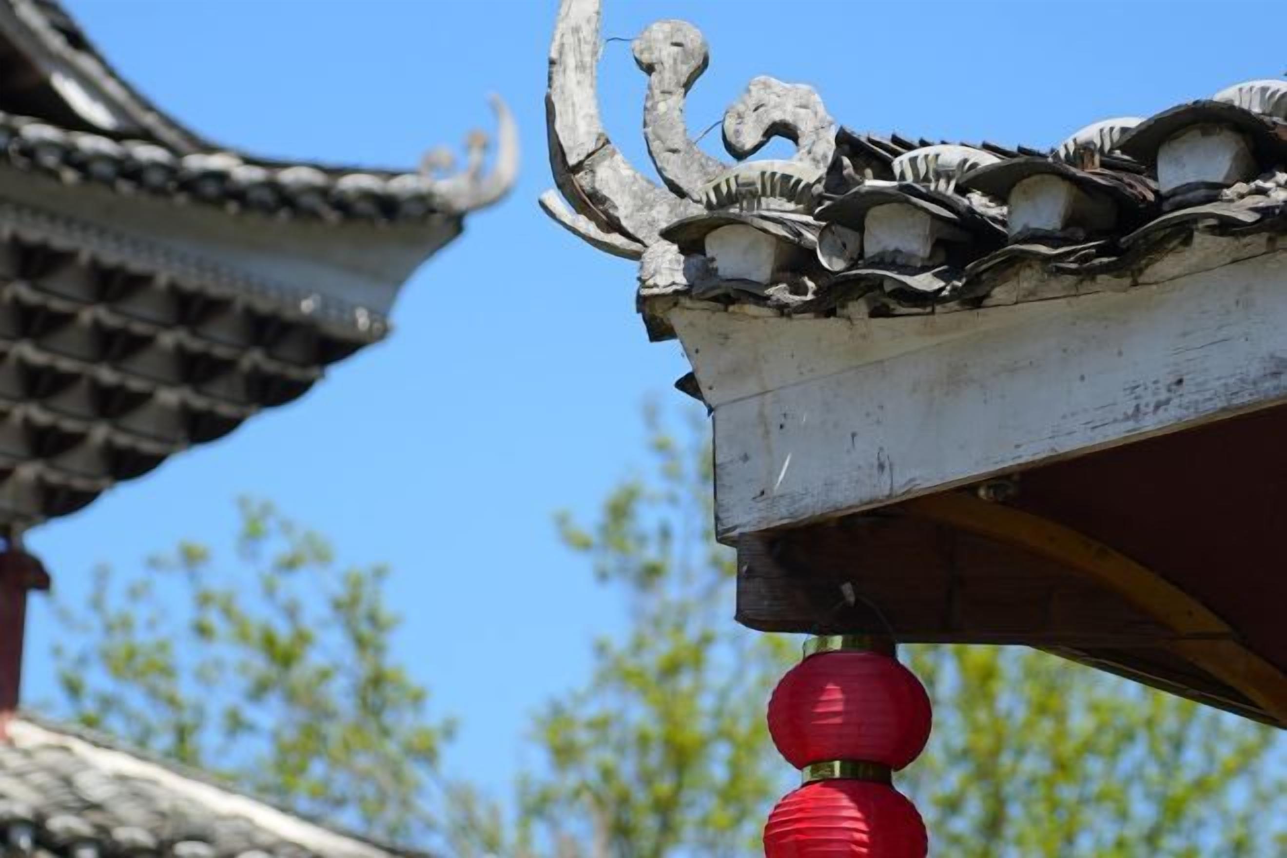 A traditional roof with ornate decorations and a red lantern.
