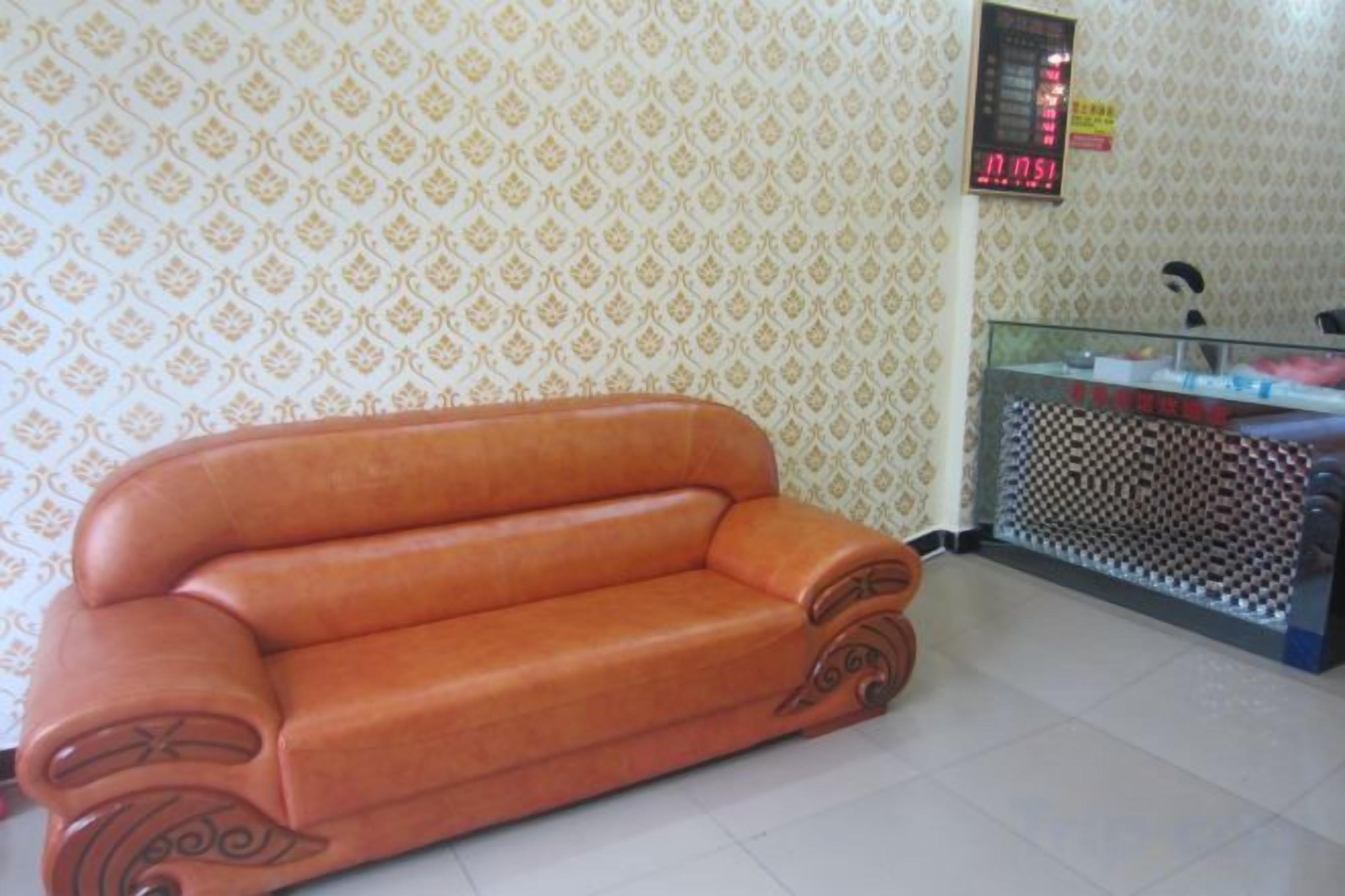 A room with a sofa, a glass partition, and patterned wallpaper.
