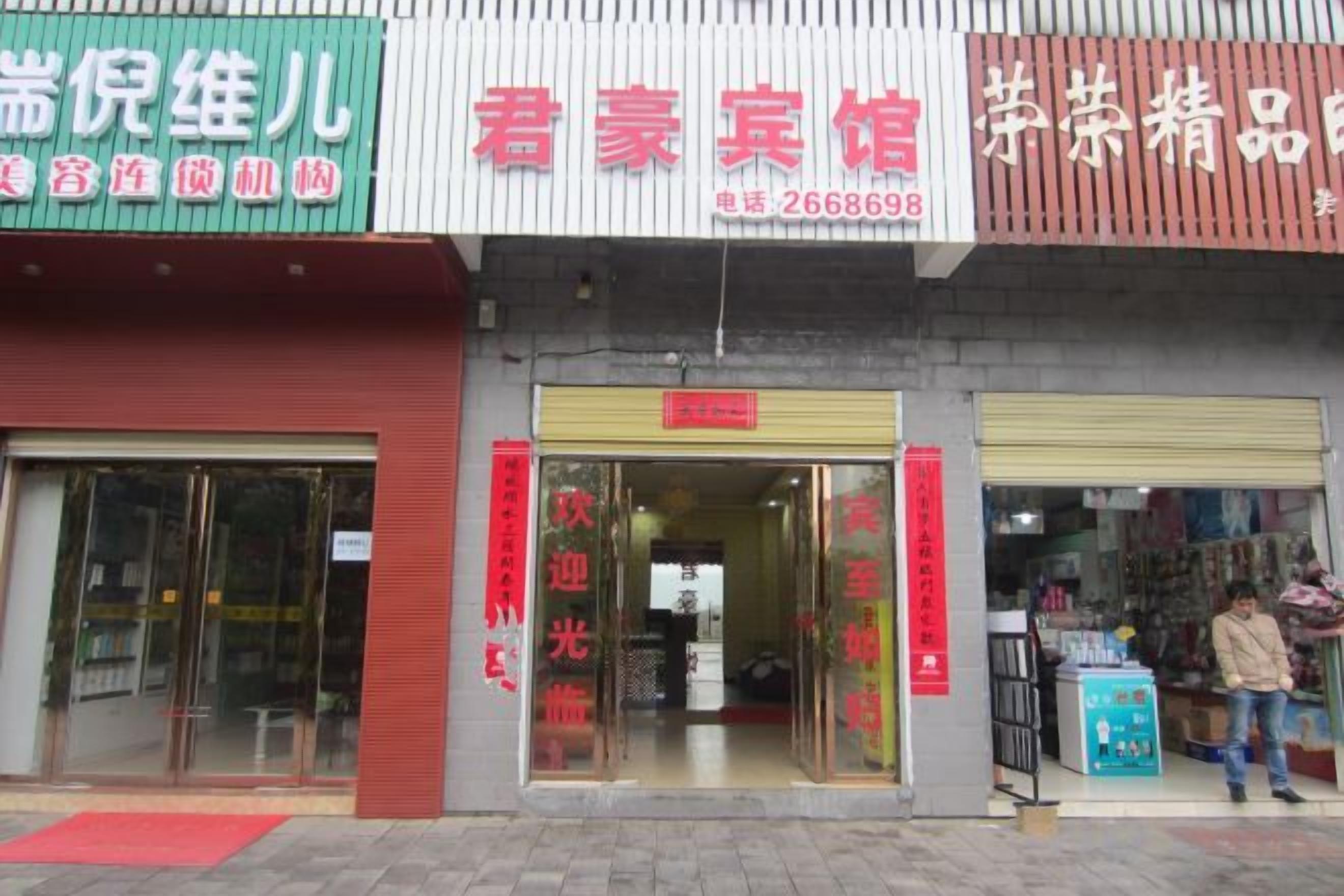 A storefront with a red signboard, a glass entrance, and a person standing outside.