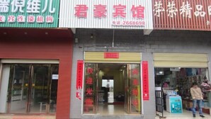 A storefront with a red banner, a glass door entrance, and a person standing outside. - Chenzhou Junhao Hotel (Chenzhou)