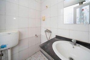 Un baño con azulejos blancos, un lavabo blanco y un espejo con diseño floral.