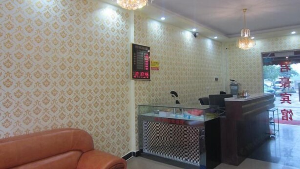 A reception area with patterned wallpaper, a reception desk, a clock, and a seating area. - Chenzhou Junhao Hotel (Chenzhou)