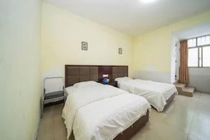 Habitación de hotel con dos camas, una silla, una mesita de noche y una ventana con cortinas.