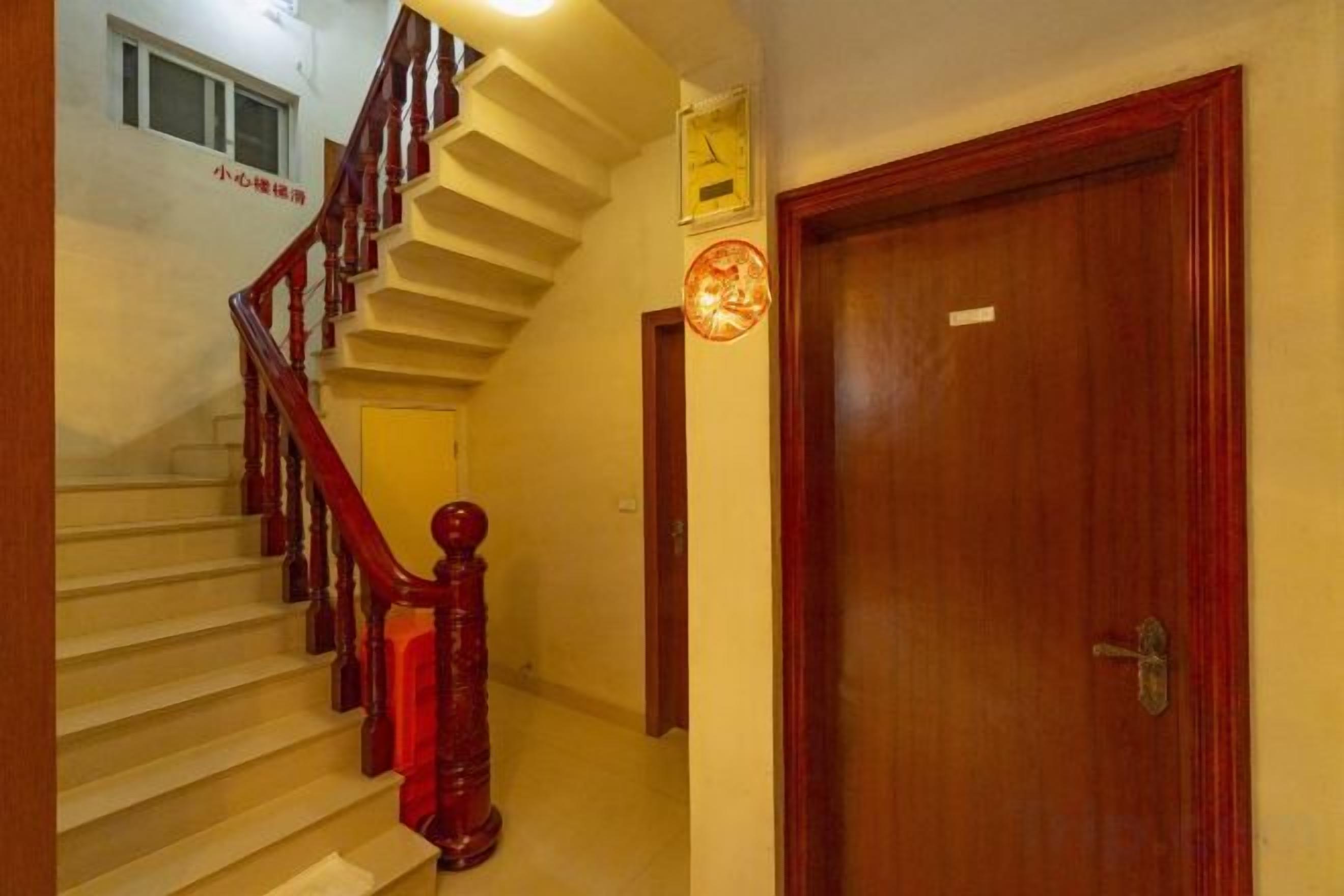 A staircase with wooden handrails and a red accent, leading to a door with a round, red decorative plate.