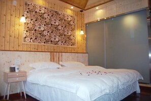 Une chambre aux murs lambrés, avec un lit, une table de chevet et une étagère murale où sont exposées des bûches de bois.