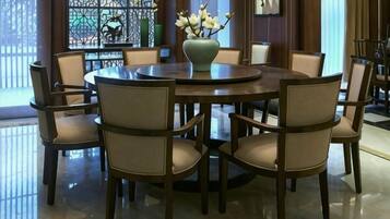 A round dining table with six chairs, a vase with flowers, and a window with decorative glass.