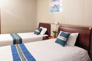 Two single beds with wooden headboards, white bedding, and blue decorative pillows.