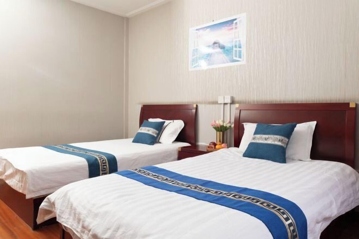 Two single beds with wooden headboards, white bedding, and blue decorative pillows.