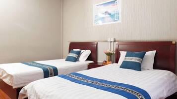 Two single beds with wooden headboards, white bedding, and blue decorative pillows.