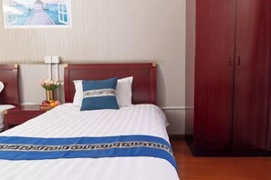 A hotel room with a large bed, a wooden headboard, a nightstand with a vase of flowers, and a wardrobe.