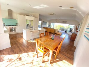 A spacious kitchen with a central island, a dining area with wooden chairs, and a large window providing natural light. - Russell's Secluded Secret (Russell)