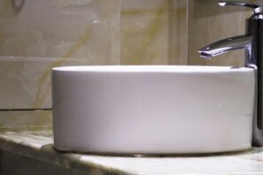 A white bathroom sink with a modern faucet on a marble countertop. - Linyuan Hotel (Jinhua)