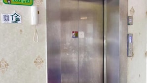 An elevator with a metallic finish, a wall-mounted phone, and a QR code sticker. - Linyuan Hotel (Jinhua)
