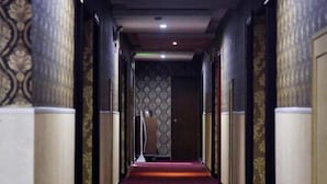 A hallway with patterned wallpaper, a red carpet, and a door at the end. - Linyuan Hotel (Jinhua)