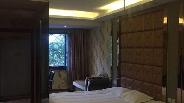 A hotel room with a bed, a chair, a desk, and a window with curtains. - Linyuan Hotel (Jinhua)