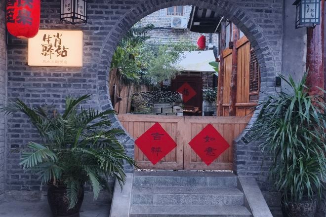 An entrance with a brick archway, a wooden gate, and red decorations.