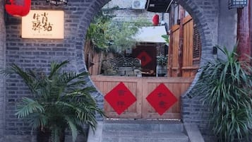 An entrance with a brick archway, a wooden gate, and red decorations.