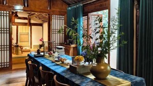 Et traditionelt japansk værelse med tatamigulv, et lavt bord med blåt dug og en stor vase med blomster.