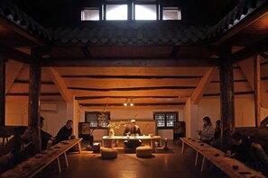 A traditional Japanese room with tatami flooring, a low table, and a ceiling with wooden beams.