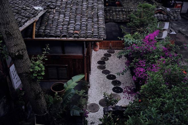 A traditional Japanese-style building with a tiled roof, a wooden entrance, and a gravel pathway leading to the door.
