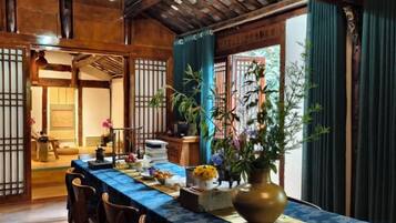 A traditional Japanese-style room with tatami flooring, a low table with a blue tablecloth, and a large vase of flowers.