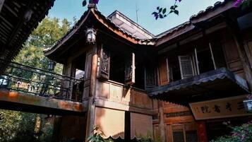 Un edificio de madera tradicional con balcón, una señal y un puente.