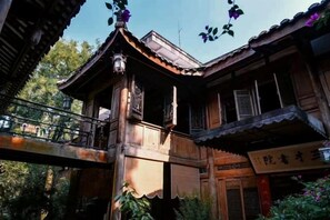 A traditional wooden building with a balcony, a signboard, and a bridge.