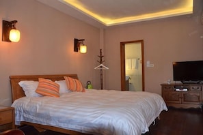A bedroom with a bed, bedside tables, a TV, and a wardrobe.