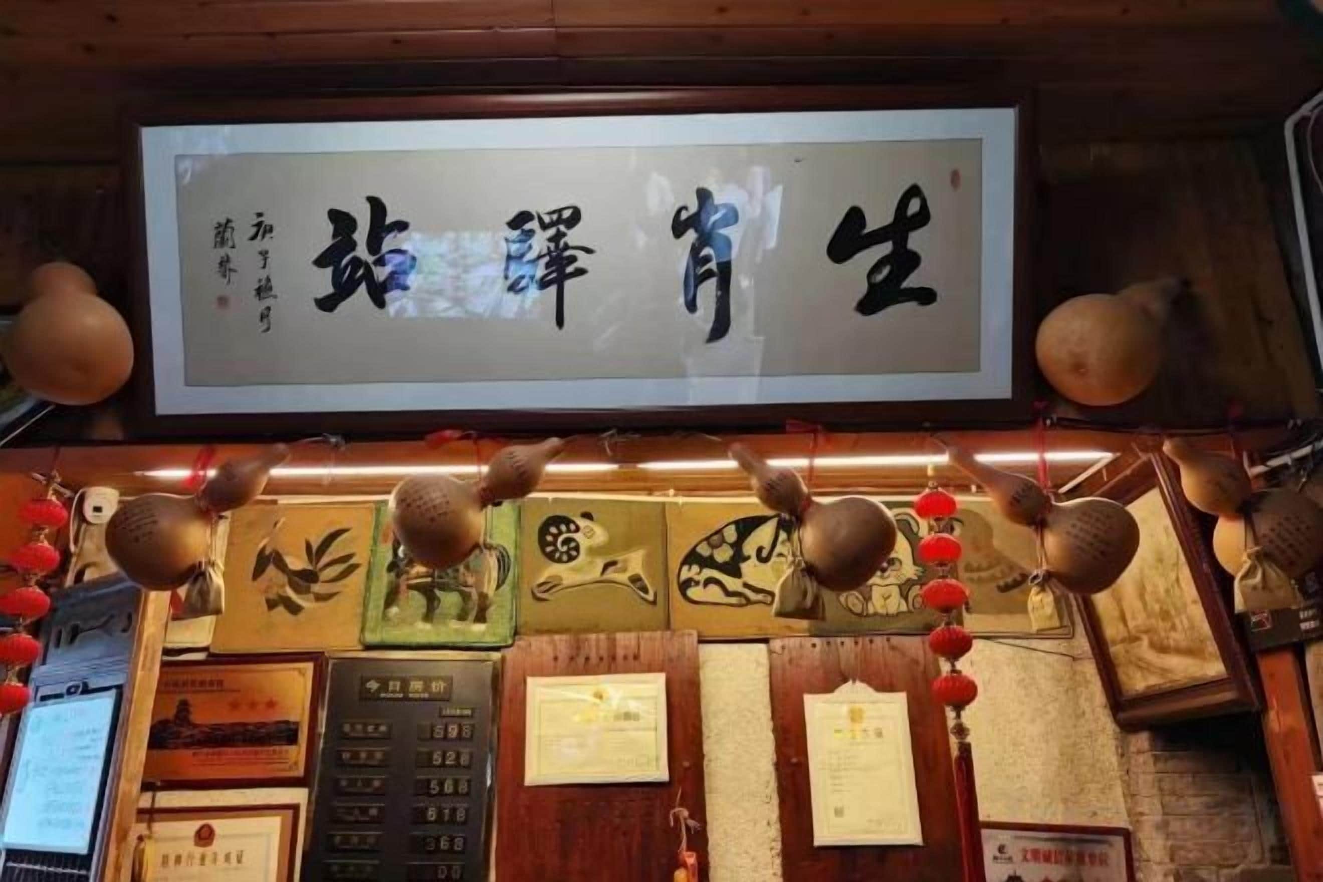 Un restaurante chino tradicional con un letrero, obras de arte enmarcadas y certificados en la pared.