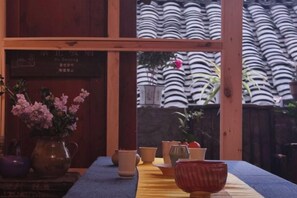 Una habitación japonesa tradicional con suelo de tatami, una mesa de madera baja y vista a una valla de bambú.