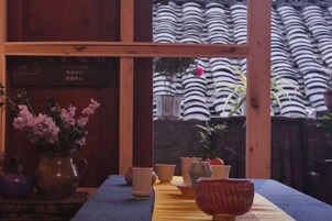 Una habitación japonesa tradicional con suelo de tatami, una mesa de madera baja y vista a una valla de bambú.