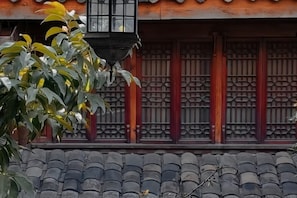 A traditional building with a tiled roof and a window with a lattice design. - Tianyi Youth Hostel (Langzhong)