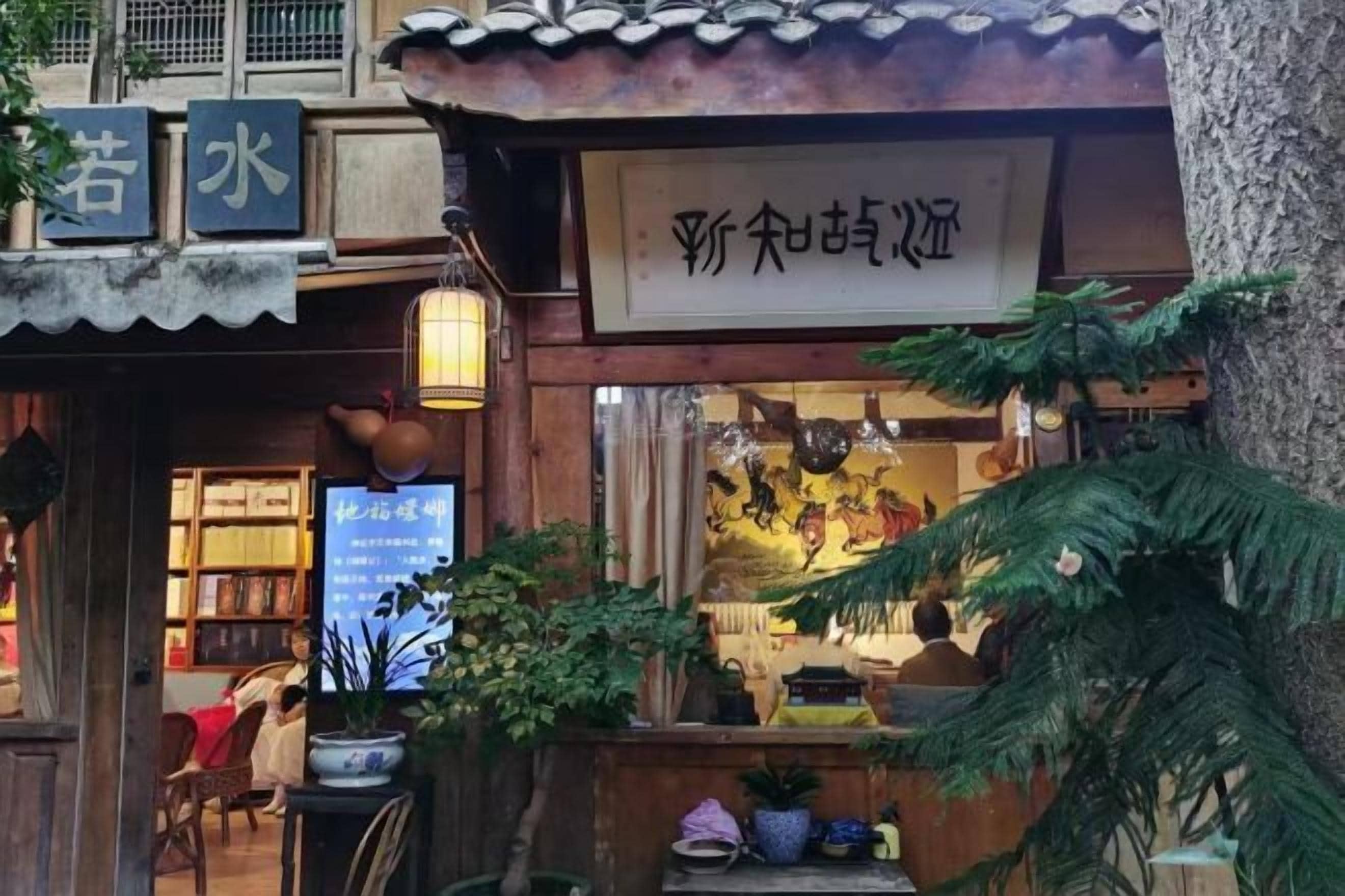 Una casa de té tradicional china con un letrero, estructura de madera y plantas en macetas.