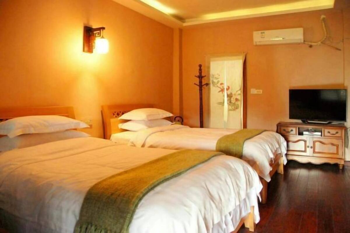 Habitación de hotel con dos camas, un televisor y aire acondicionado instalado en la pared.
