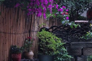Una valla de bambú, plantas en macetas y una reja metálica decorativa.