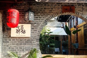 Una entrada de ladrillo en arco con un letrero, faroles y una puerta de madera.