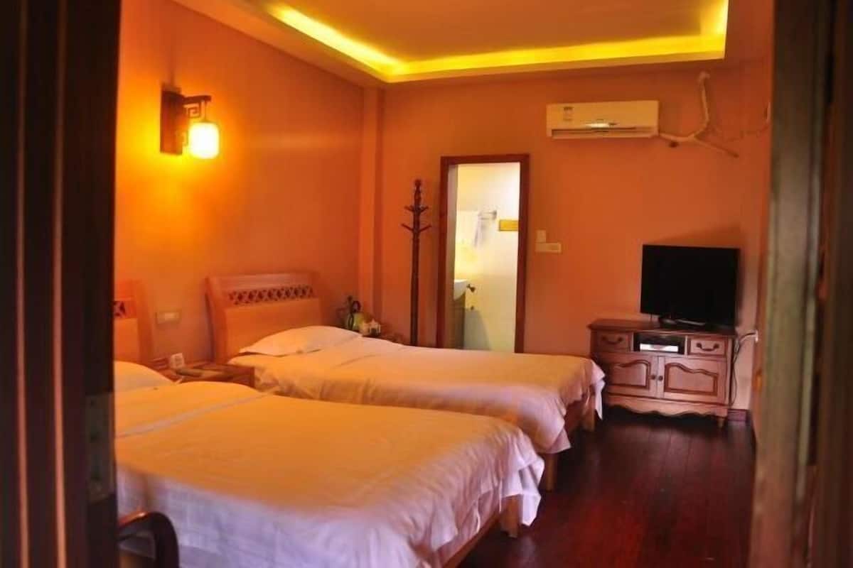 Habitación de hotel con dos camas, televisión, cómoda y espejo.
