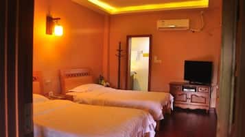 A hotel room with two beds, a TV, a dresser, and a mirror.