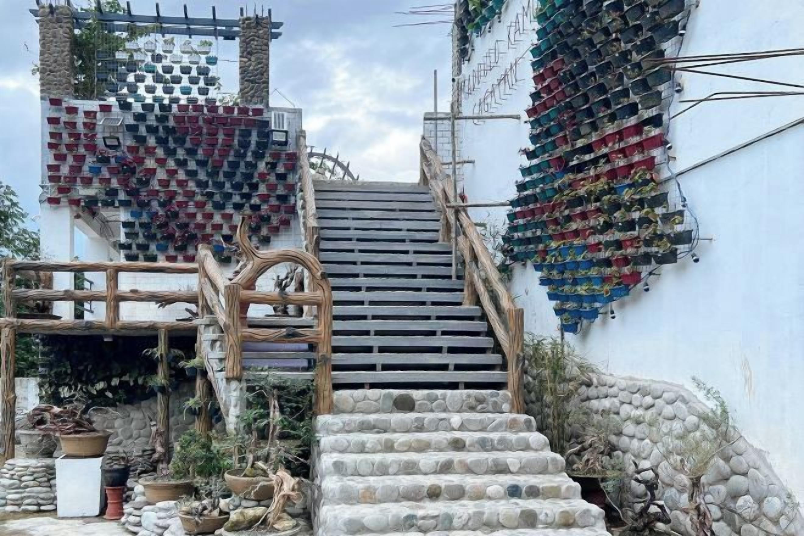 Una escalera conduce a un edificio con una decoración mural con forma de corazón y una estructura de madera a la izquierda.