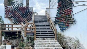 Una escalera conduce a un edificio con una decoración mural con forma de corazón y una estructura de madera a la izquierda.