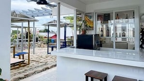 A modern kitchen with a white countertop, a hanging light fixture, and a view of the outdoor patio area. - UrbanView @ Balzain East Tuguegarao City by RedDoorz (Tuguegarao)
