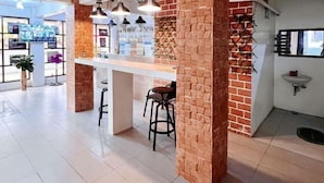 A modern bar area with a brick accent wall, bar stools, pendant lighting, and a white countertop. - UrbanView @ Balzain East Tuguegarao City by RedDoorz (Tuguegarao)