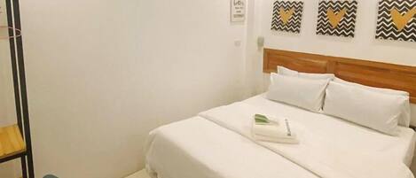 A single bed with white bedding, a wooden headboard, and a small bedside table with a lamp.