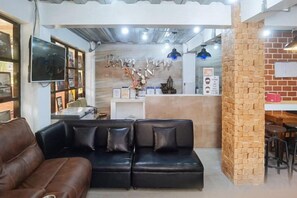 Un área de recepción con un sofá de cuero negro, un mostrador de recepción y una pared de ladrillo decorativa.