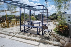 Una obra en construcción con estructuras metálicas y bancos, rodeada de rocas y plantas.
