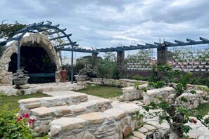 A garden with a stone archway, potted plants, and a pergola structure. - UrbanView @ Balzain East Tuguegarao City by RedDoorz (Tuguegarao)