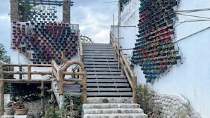 A staircase with stone steps and wooden railings, surrounded by potted plants and a wall with hanging laundry. - UrbanView @ Balzain East Tuguegarao City by RedDoorz (Tuguegarao)