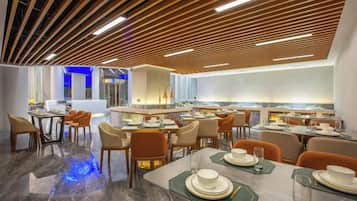 Un comedor moderno con varias mesas y sillas, una isla central y un diseño de techo contemporáneo.