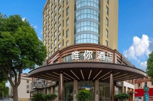 Entrada de hotel con un toldo curvo y señalización en un idioma extranjero.